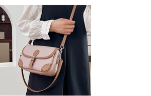 Detail of pink pebbled leather crossbody bag with brown trim and silver buckle on model