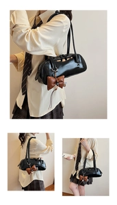 Vue détaillée du sac cylindrique en cuir verni noir avec pendentif nœud marron en relief