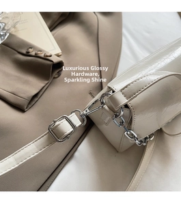 Close-up of cream leather shoulder bag with glossy wave texture and silver metal hardware