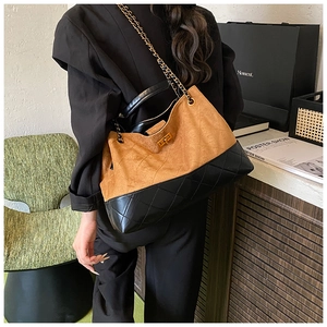 Détail d'un grand sac cabas en daim marron et cuir matelassé noir avec bandoulière