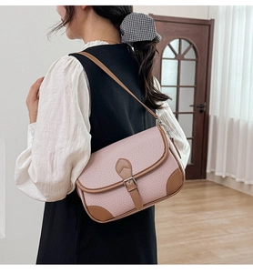 Close-up of pink pebbled leather shoulder bag with brown trim on a fashion model