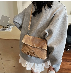Detailed view of brown denim crossbody bag featuring geometric stitching and adjustable strap
