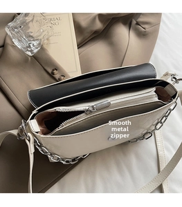 Top view of cream and black handbag showing silver zipper and smooth internal storage