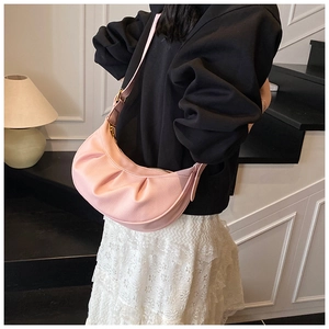 Vue détaillée de la texture en cuir rose grainé et du design plissé sur le sac à main