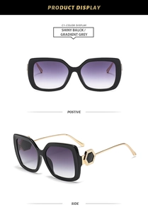 Detail view of square black frames with gold metal temples and hexagonal jewelry accents