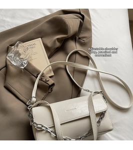 Detail of cream baguette bag with silver chain on textured leather and adjustable strap