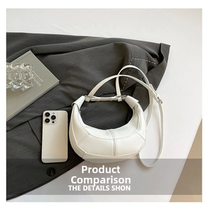 Detail of white crescent bag showing cross-stitch seam textures and adjustable strap