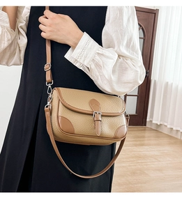 Close-up of vintage brown lychee grain leather crossbody bag with silver buckle detail