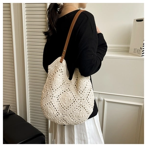 Detail of cream crochet tote bag with open-knit texture and brown leather shoulder straps