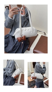 Détail d'un sac baguette blanc avec double fermeture éclair et pendentif nœud marron