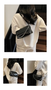 Close-up of a black patent leather underarm bag with a stylish chunky silver chain strap