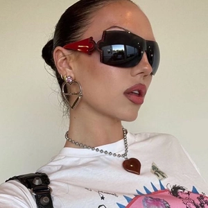 Macro side view of red wide temple Y2K rimless shield sunglasses and heart earrings
