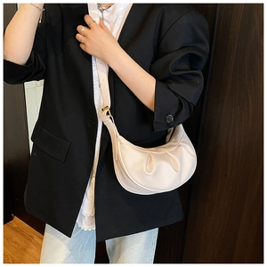 Détail du sac demi-lune beige en cuir grainé avec texture plissée porté par le mannequin