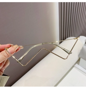 Detail of a minimalist gold metal eyewear frame with luxury chain aesthetic and geometric lines