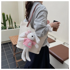 Dettaglio della borsa tote in tela bianco avorio con coniglio di peluche 3D e manici marroni