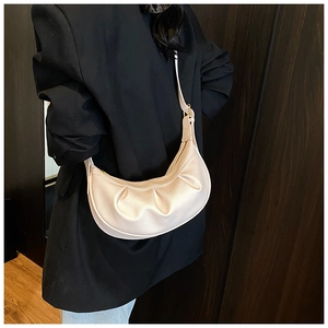 Détail du sac bandoulière demi-lune plissé beige avec texture litchi sur costume noir