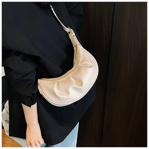 Détail du sac croissant beige clair à plis avec texture grainée et zip doré élégant