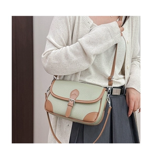 Detail of green pebble leather crossbody bag with brown trim and adjustable strap