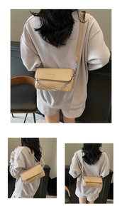 Detail view of khaki baguette bag featuring a silver metal chain and adjustable strap