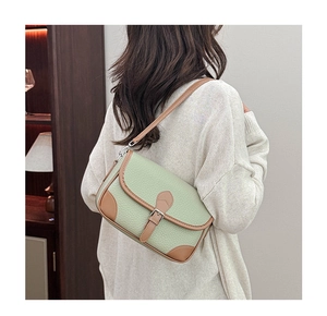 Detail of light green litchi grain leather bag with brown piping and vintage buckle