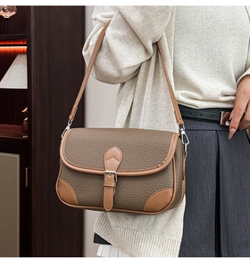 Close-up of brown litchi pattern leather texture and silver buckle on a stylish bag