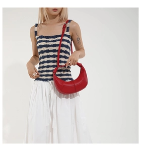 Red lychee grain leather crescent bag styled with a blue and white striped vest outfit