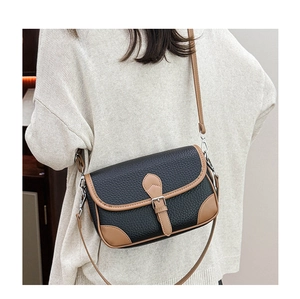 Close-up of black litchi grain leather crossbody bag with brown trim and silver hardware