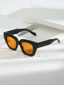 Détail de lunettes de soleil carrées noires avec verres orange sur pierre blanche
