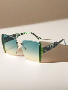 Close-up of oversized rimless sunglasses featuring green-yellow gradient lenses and gold nose bridge