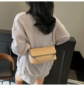 Detailed view of the glossy light brown leather bag featuring a chunky silver metal chain