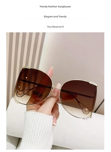 Detail of gradient brown lenses and metal temples with white pearl accents on large frame sunglasses