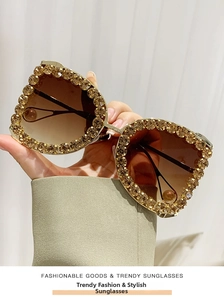 Detailed view of luxury gold sunglasses frame with amber rhinestones and gradient lenses