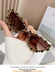 Close-up of cat-eye sunglasses with crystal-encrusted metal frame and brown gradient lenses