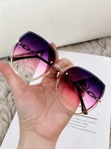 Close-up of frameless butterfly sunglasses with gradient lenses and gold chain temples