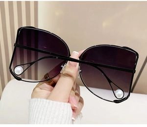 Detail of oversized cat-eye sunglasses with gradient purple lenses and pearl accents