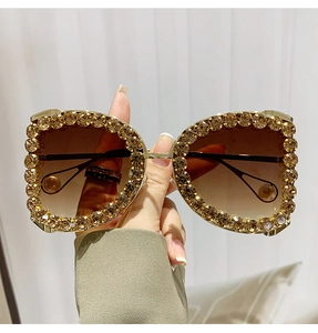 Detail of luxury D-frame sunglasses with golden rhinestones and pearl temple tips