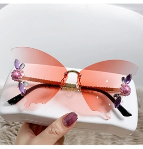 Close-up of butterfly rimless sunglasses with pink gradient lenses and floral rhinestone details