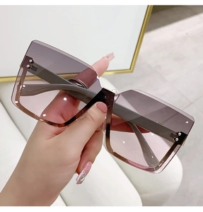 Detail of rimless square sunglasses featuring gradient lenses and gold metal stud accents