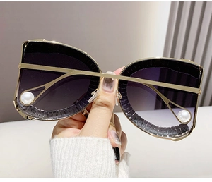Detail of luxury cat-eye sunglasses with gold metal frame and pearl accents
