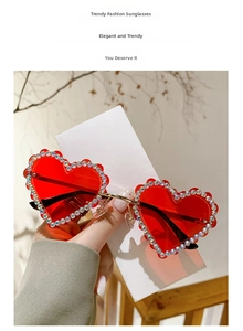 Détail de lunettes de soleil cœur sans monture avec strass brillants et verres teintés rouges