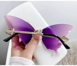 Détail de lunettes de soleil papillon sans monture avec verres dégradés violets et branches dorées