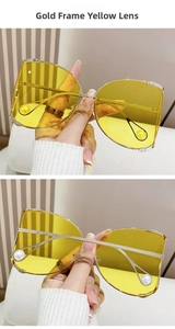 Close-up of D-frame gold metal sunglasses with yellow lenses and pearl temple tips