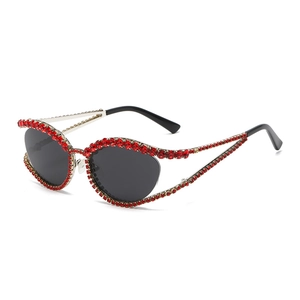 Lunettes de soleil œil-de-chat à strass rouges et verres gris foncé sur fond blanc uni