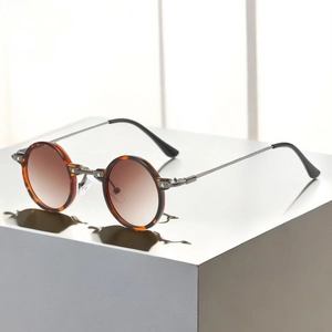 Macro detail of round tortoiseshell sunglasses with gradient lenses and metal temples