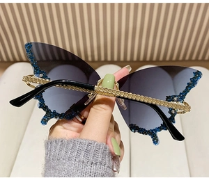 Detailed view of butterfly sunglasses lens edge adorned with sparkling blue rhinestones