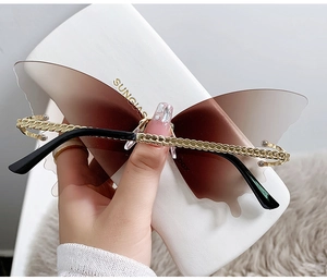 Détail de lunettes de soleil papillon sans monture avec verres dégradés et branches chaînes