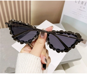 Detailed view of black cat-eye sunglasses with unique wavy textured frames held by hand