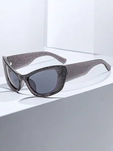 Close-up of cat eye sunglasses with grey translucent frames and sparkling glitter details