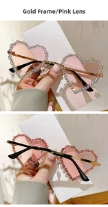Détail de lunettes de soleil cœur sans monture dorée, verres roses et bord en strass