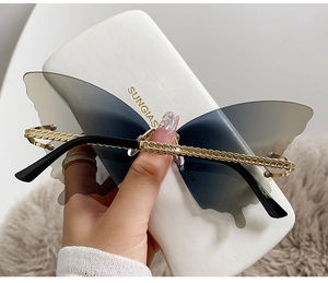 Détail de lunettes papillon sans monture avec verres dégradés et branches dorées